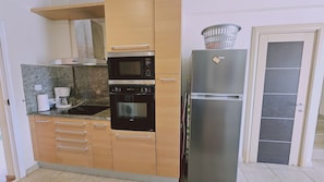 A compact kitchen with a microwave, oven, and refrigerator. - 123 AN - Stay Nissi House (Ayia Napa)
