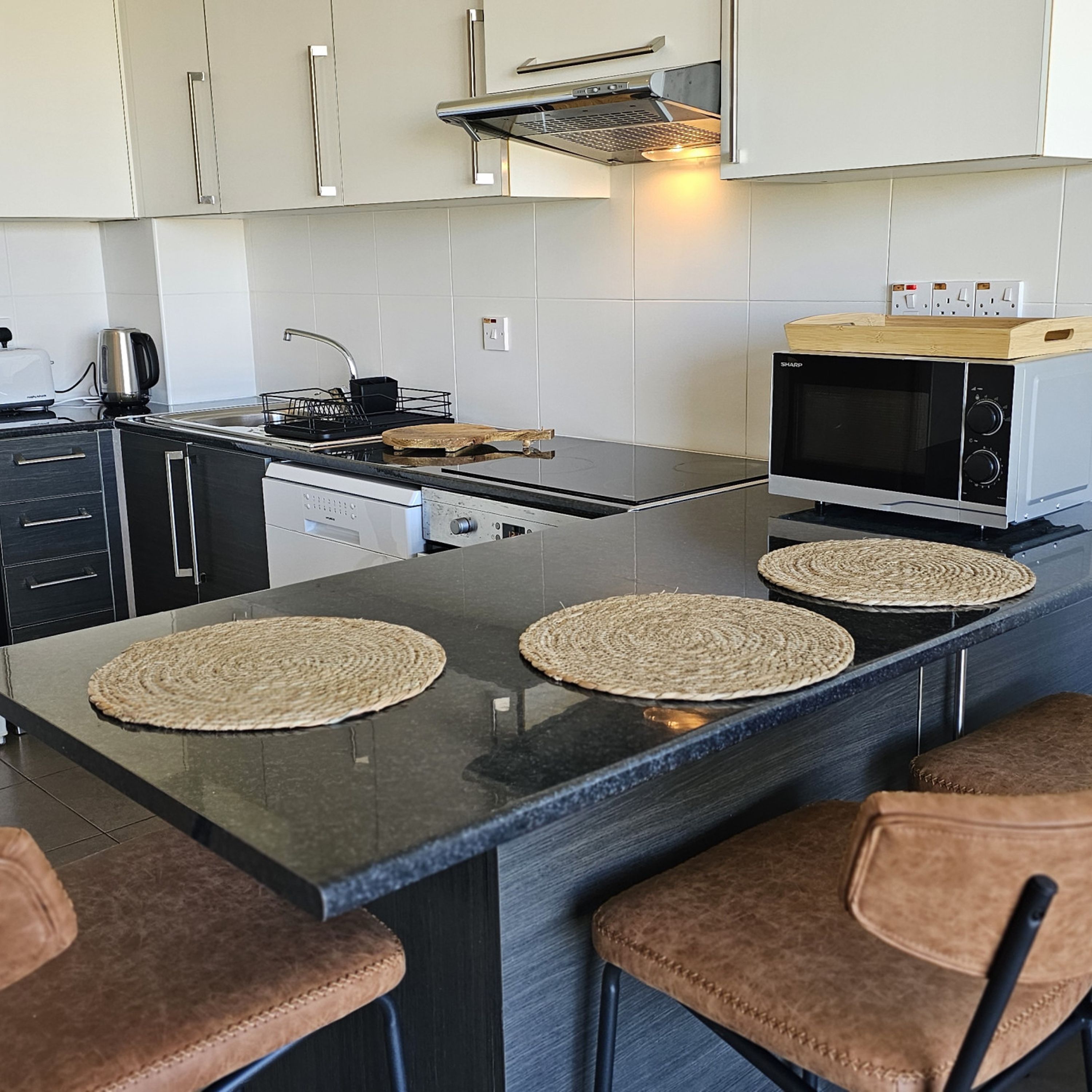 A modern kitchen with a central island, stainless steel appliances, and bar stools.