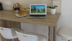 A modern kitchen with a laptop on the counter, a coffee maker, and a potted orchid. - 112 AN - Stay Paradise Sands Studio (Ayia Napa)