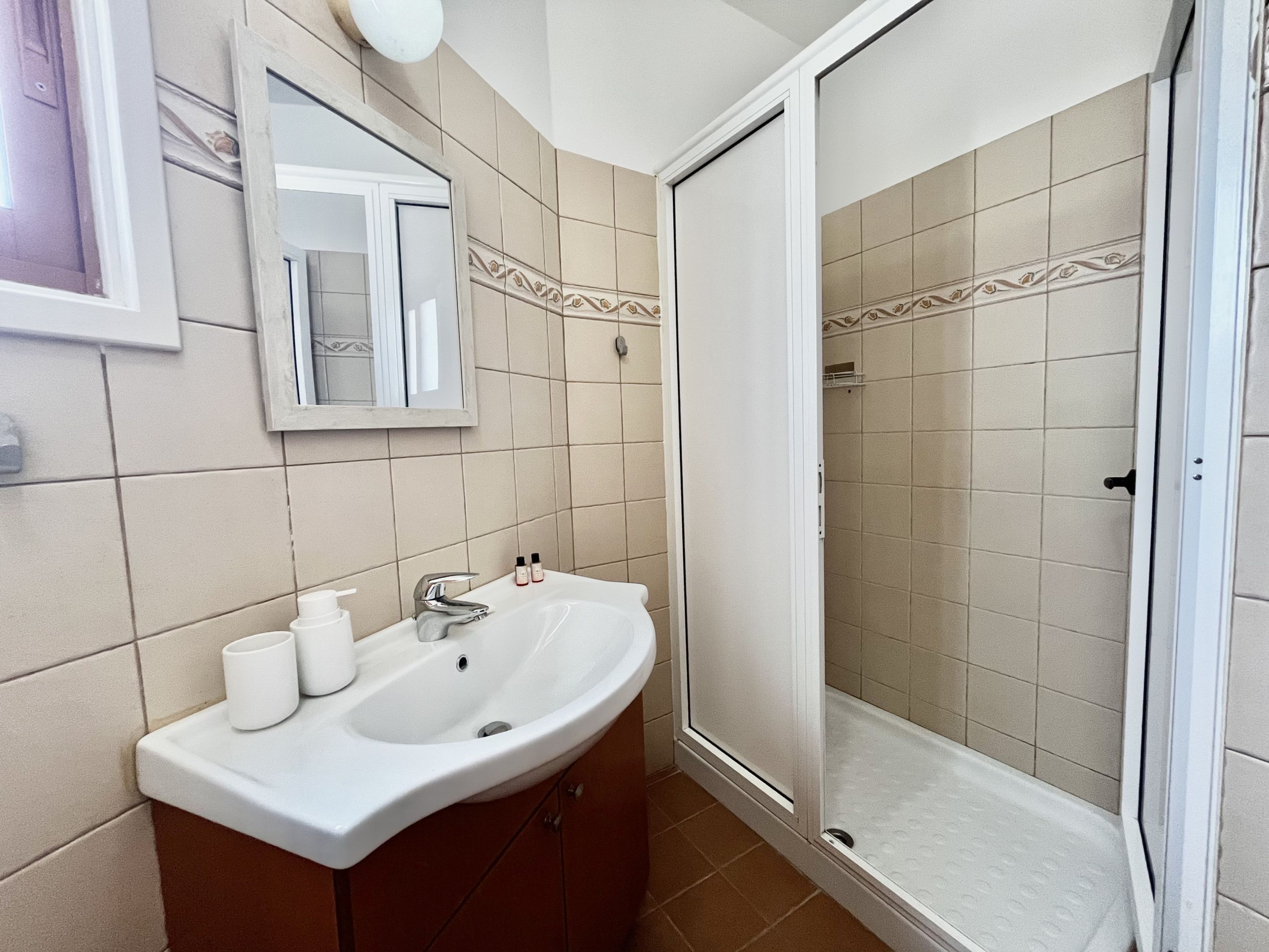 A bathroom with a sink, mirror, and shower.