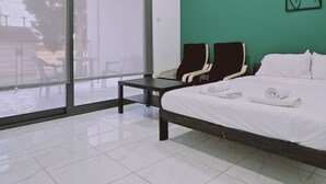 Camera d'albergo moderna con un letto grande, una scrivania e una sedia. È presente una porta scorrevole in vetro che dà su uno spazio all'aperto.
