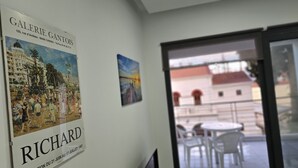 Una stanza con un poster di uno skyline urbano, un piccolo quadro e vista su un edificio attraverso una porta vetrata.