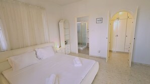 A bedroom with a large bed, a walk-in closet, and a bathroom with a glass shower. - 122 VOR - Stay Cactus House (Oroklini)