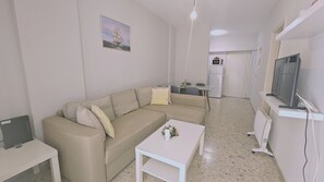 A living room with a beige sofa, a small white coffee table, and a television on a stand. - 126 NIC - Stay Incity Apartment (Nicosia)