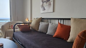 A modern bedroom with a bed, a chair, a table, and a painting on the wall. - 119 LCA - Stay Dreamy Seaside Apartment (Larnaca)