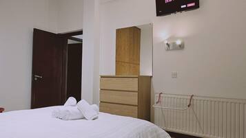 Habitación de hotel con una cama, un armario de madera, un televisor de pared mostrando 'NETFLIX' y un radiador.