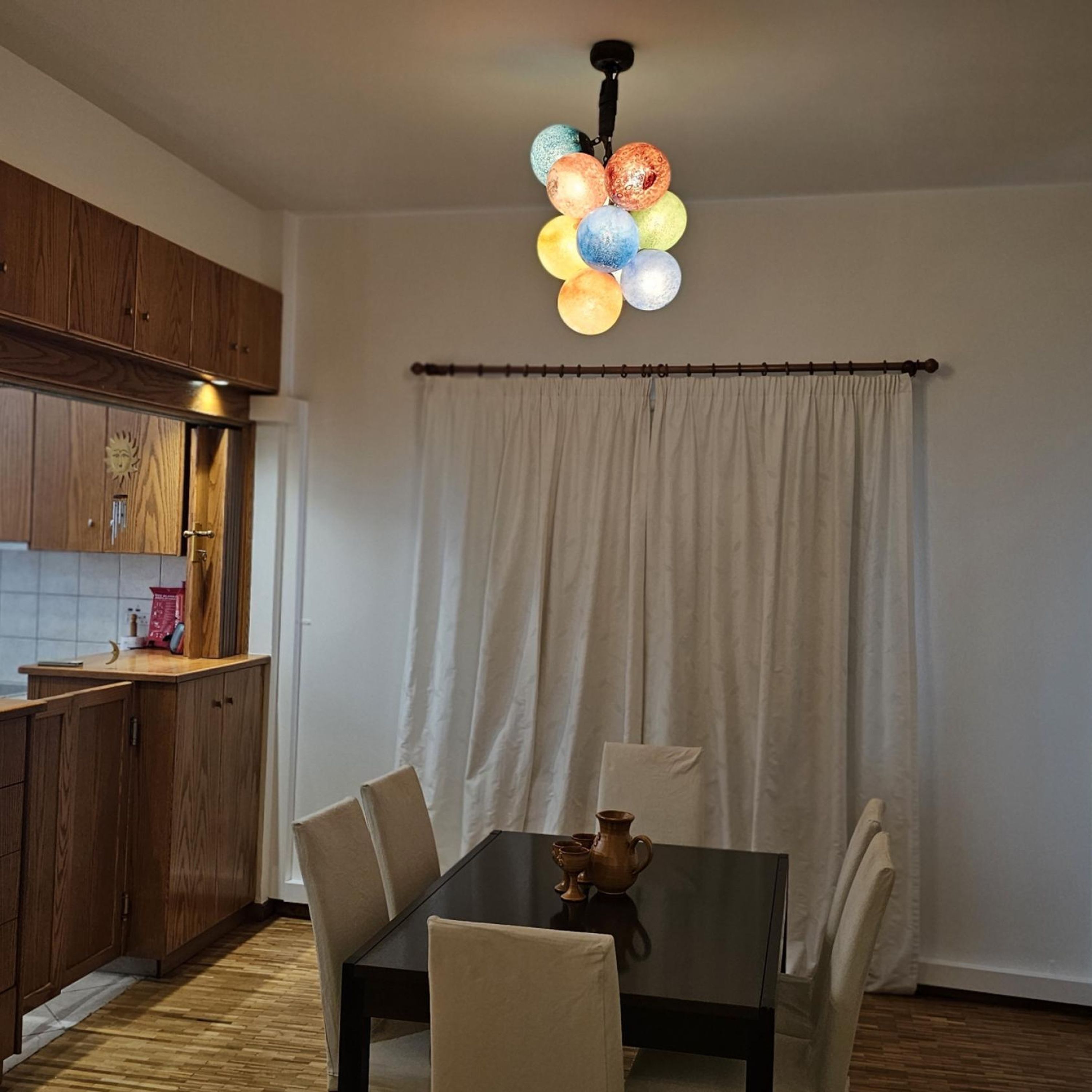 A dining area with a table and chairs, a kitchen with wooden cabinets, and a curtain.