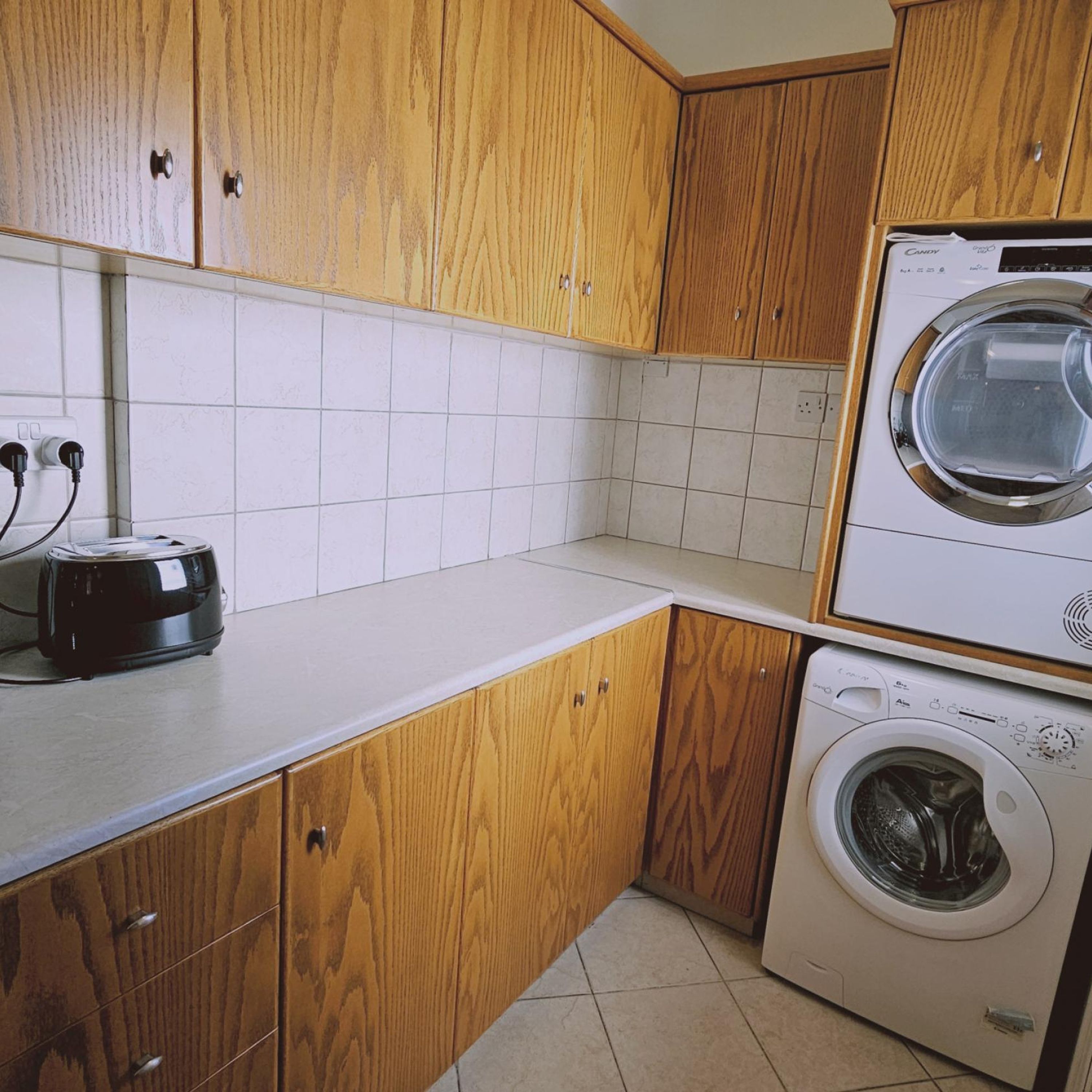 Una cocina con armarios de madera, un tostador y una lavadora.