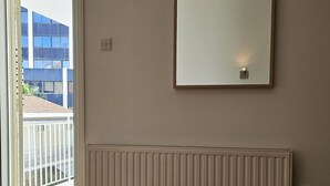 Une chambre d’hôtel avec une grande fenêtre, un radiateur et un miroir au mur.