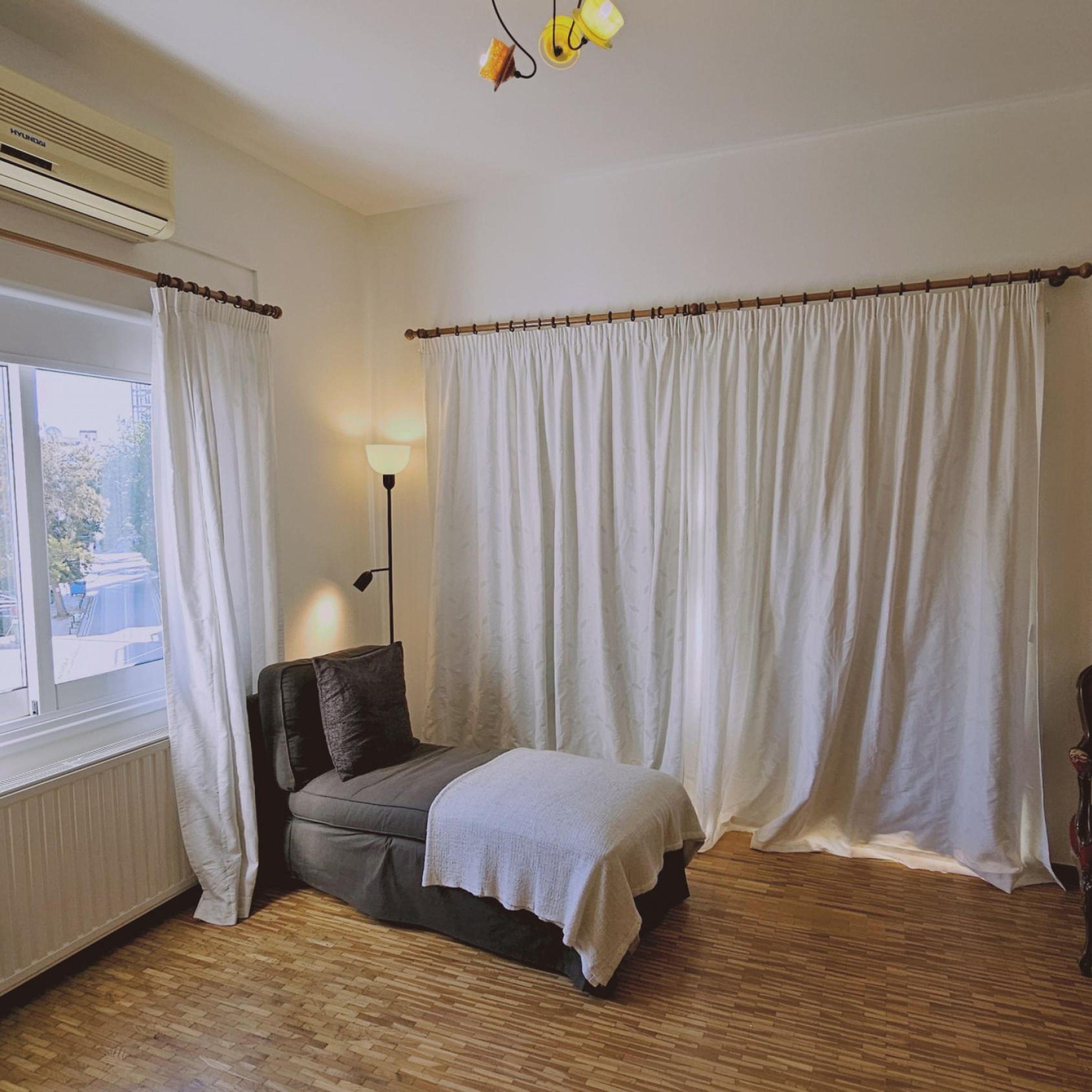 Huone, jossa on sänky, ikkuna verhoilla, patteri ja lamppu.