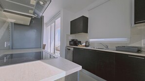 A modern kitchen with dark cabinets, a stainless steel sink, and a built-in oven.