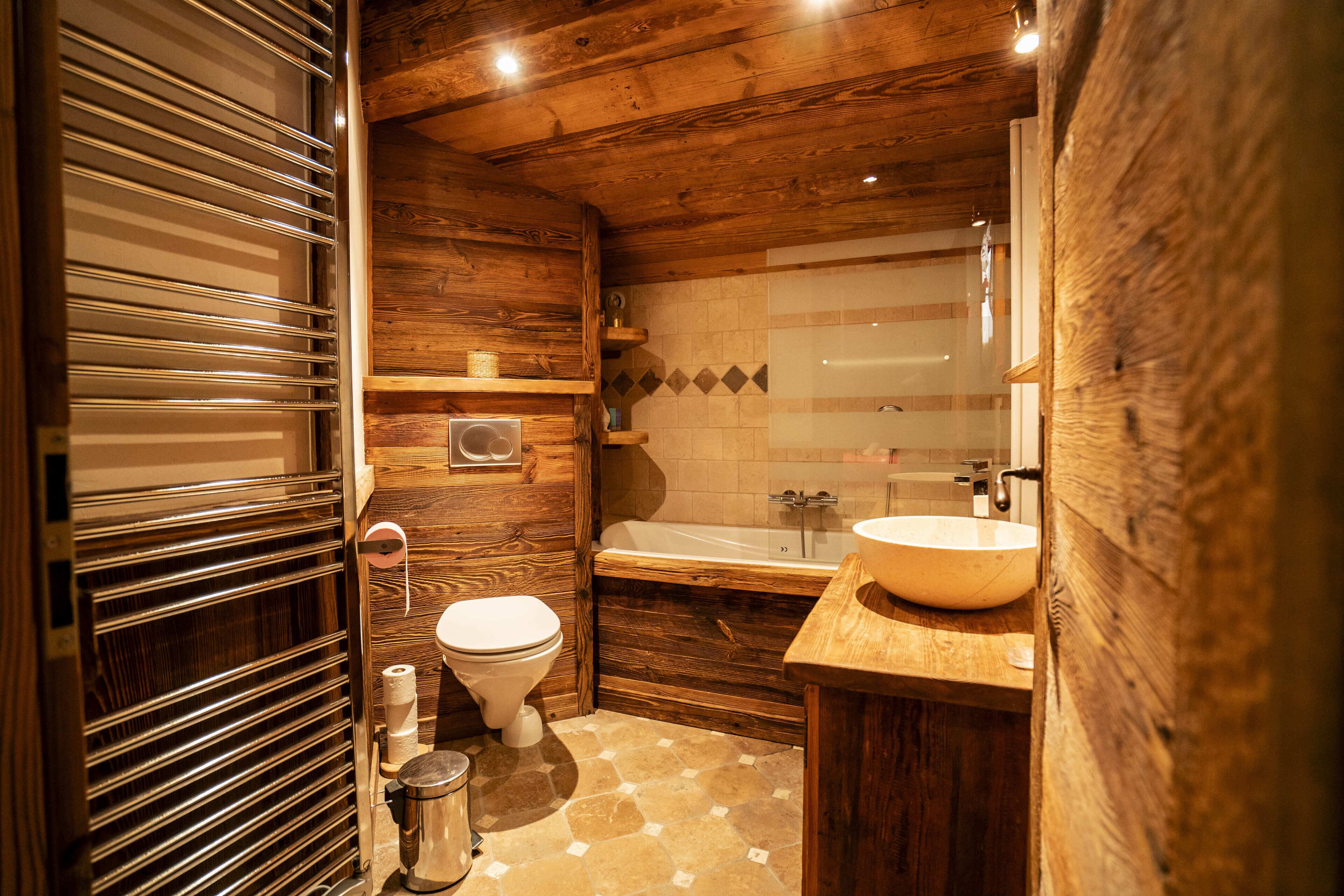 Un baño de madera con inodoro, lavabo y bañera.