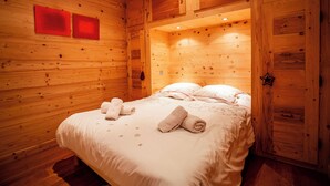 Ein Zimmer einer Holzhütte mit einem Bett, zwei roten Wandfeldern und einer Sterndeko an der Tür.