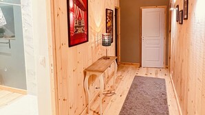 A hallway with wooden walls, a bench, a framed poster, and a door at the end. - Gite de Groupe Lozère Aubrac (Peyre en Aubrac)