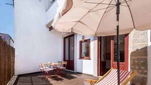 Un patio con una mesa y sillas, una silla reclinable a rayas y una sombrilla.