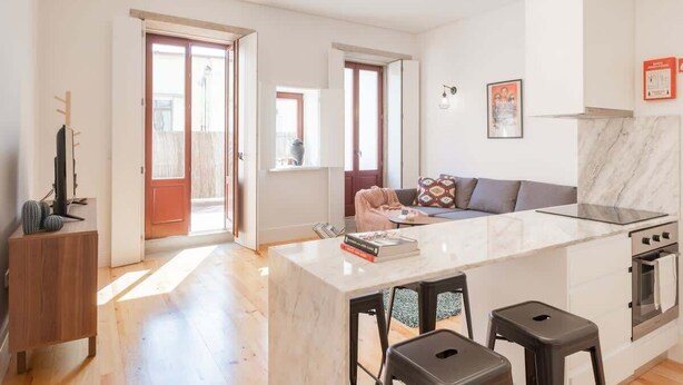 Una cocina moderna con encimera de mármol, horno empotrado y una zona de comedor con taburetes.