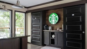 A kitchen with dark wood cabinets, a black door with a Starbucks logo, and a window overlooking greenery. - Wimberley | Hot Tub+Fire Pit+Pickleball | Sleeps 6 (Wimberley)