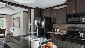 A modern kitchen with dark wood cabinets, stainless steel appliances, and granite countertops. - Wimberley | Hot Tub+Fire Pit+Pickleball | Sleeps 6 (Wimberley)