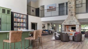 Een ruime woonkamer met een stenen openhaard, een hoge plafond en een balkon met uitzicht.