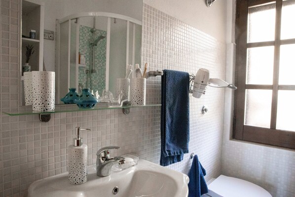 A bathroom with a white sink, a mirror, and a window.