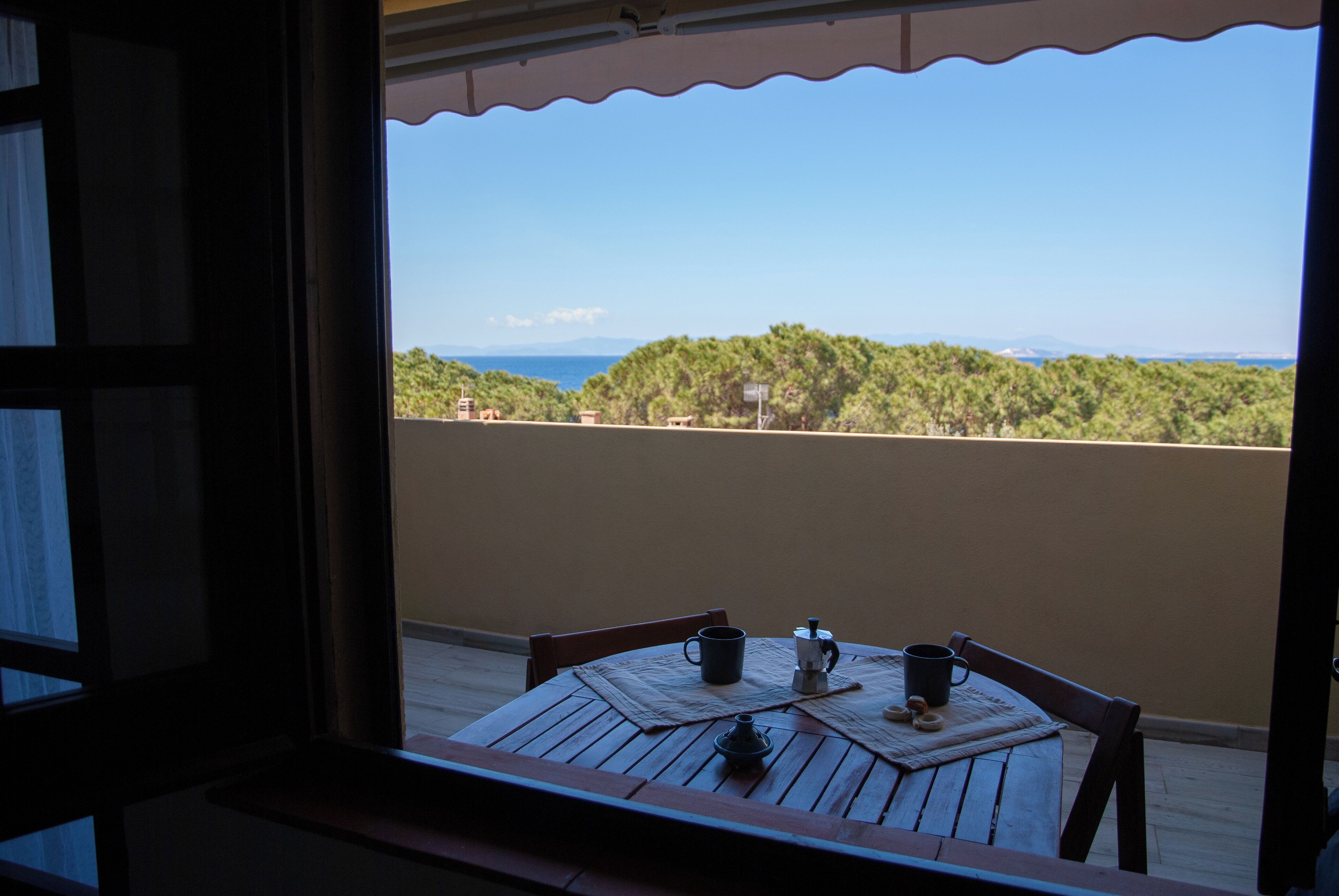A balcony with a wooden table, two cups, and a small teapot.