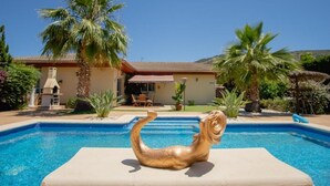 A swimming pool with a mermaid statue in the center, surrounded by palm trees and a house in the background. - 5-bed chalet in Albir, with swimming pool, AC, 20-min-walk to beach.  (l'Alfàs del Pi)