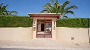 A building with a number '2' above the entrance, surrounded by well-maintained hedges and palm trees. - 5-bed chalet in Albir, with swimming pool, AC, 20-min-walk to beach.  (l'Alfàs del Pi)