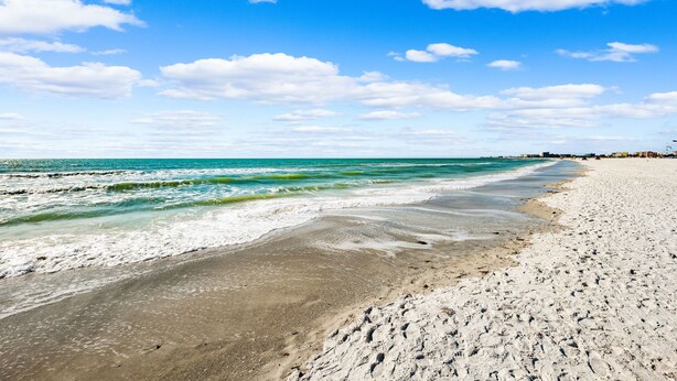 Ein Strand mit klarem, blauem Wasser und weißem Sand.