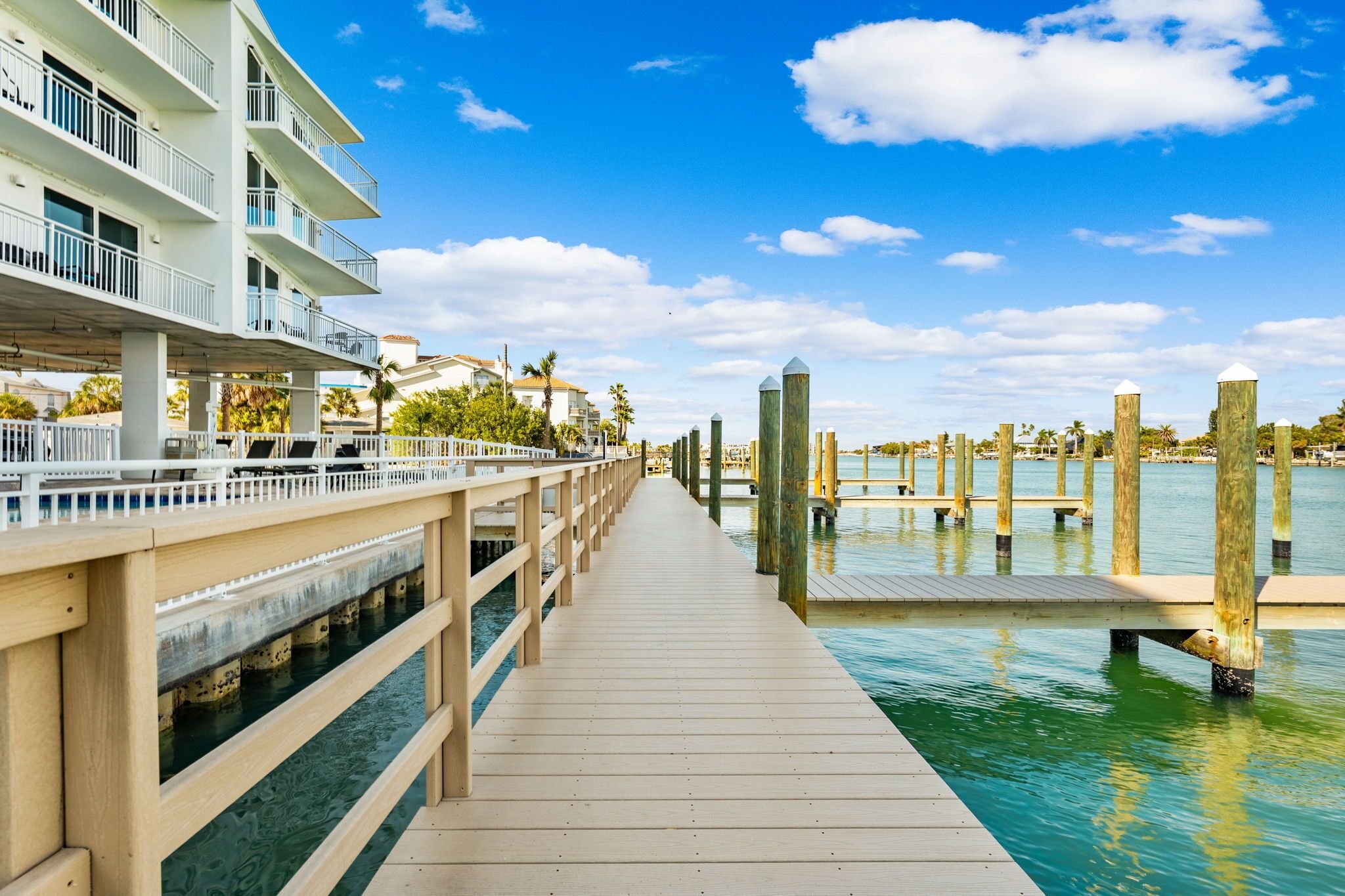 A wooden pier leading to a dock with a white building on the left.