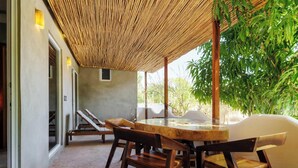 An outdoor dining area with a bamboo ceiling, wooden furniture, and a view of greenery. - Incredible Nautilus Suite in the Heart of Punta (Brisas de Zicatela)