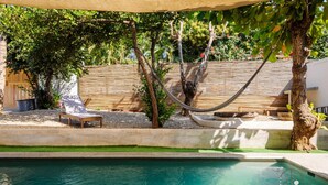 A pool area with a hammock, lounge chairs, and a wooden fence. - Incredible Nautilus Suite in the Heart of Punta (Brisas de Zicatela)