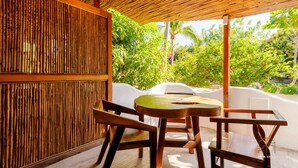 A wooden table and chairs under a thatched roof, surrounded by lush greenery. - Unmatched Modern PH Loft in the Center of la Punta (Brisas de Zicatela)