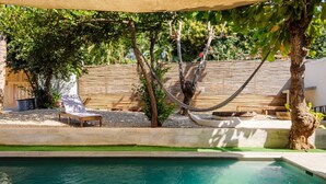 A pool area with a hammock, lounge chairs, and a wooden fence. - Spectacular Suite Steps Away From Center La Punta! (Brisas de Zicatela)