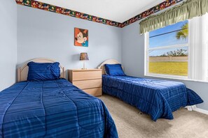 Une chambre avec deux lits, une commode, une lampe et une fenêtre donnant sur un beau paysage.