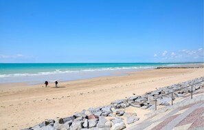 Une plage avec une digue rocheuse et un ciel bleu dégagé.