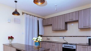 Une cuisine moderne avec des meubles en bois, un îlot central, une cuisinière et des luminaires suspendus.
