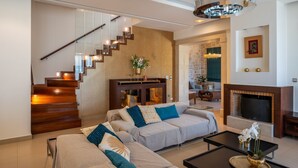 A modern living room with a staircase, a fireplace, and a dining area.