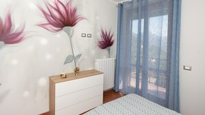 Una camera da letto con un comò in legno, un letto con copriletto decorato e una finestra con tende blu.
