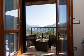 A balcony with wicker furniture, a bottle, and glasses, overlooking a mountainous landscape. - Casa Francese Relax - An Oasis of Well-being not far From the sea (Tramonti)