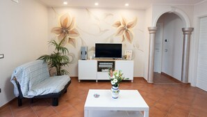 Un soggiorno con divano, tavolino, televisore e una parete decorativa.