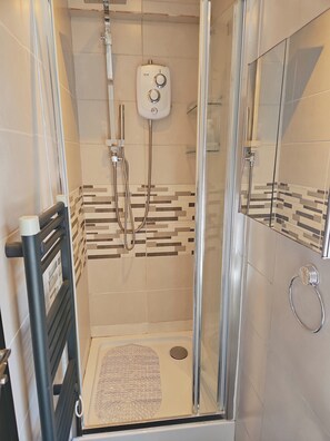 Shower area features a glass enclosure with a central showerhead and control panel.