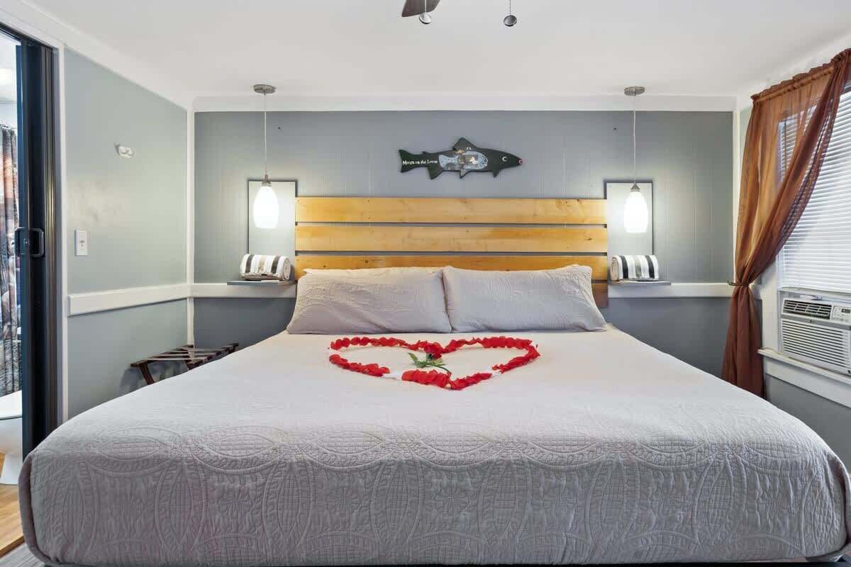 Une chambre d’hôtel avec un grand lit, une tête de lit en bois, deux lampes de chevet et un décor mural représentant des poissons.