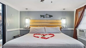 A hotel room with a large bed, a wooden headboard, two bedside lamps, and a wall-mounted fish decoration. - Mountain views Hiking by Day & Hot tub by night #2 (Carroll)