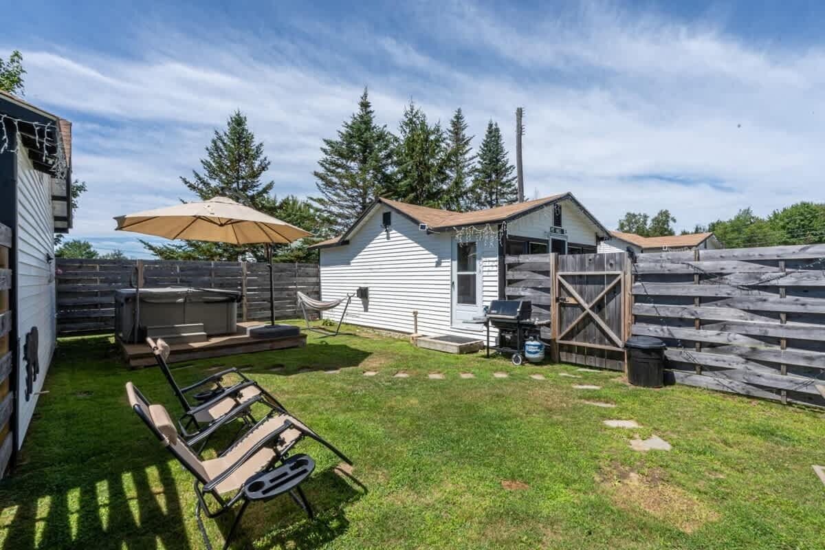 A backyard with a barbecue grill, a hammock, and a shed.