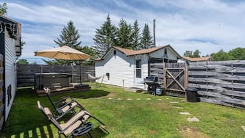 A backyard with a barbecue grill, a hammock, and a shed.