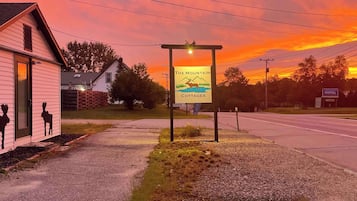 A sign for The Mountain Cottages Motel with a clear view of the surrounding area, including a small building with a door and windows, and a road in the background.