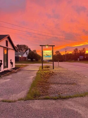 A sign for The Mountain Cottages Motel with a clear view of the surrounding area, including a small building with a door and windows, and a road in the background.