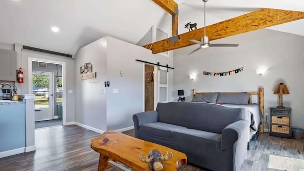 A spacious living room with a grey sofa, wooden coffee table, and a ceiling fan. - Mountain Views Hot Tub Hike Mt. Washington  #4 (Carroll)