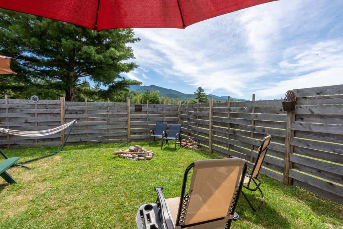 Un patio trasero con una cerca de madera, una hamaca y mobiliario exterior.