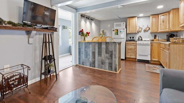 Una cocina moderna con armarios de madera, horno empotrado y zona de comedor con mesa y sillas de vidrio.